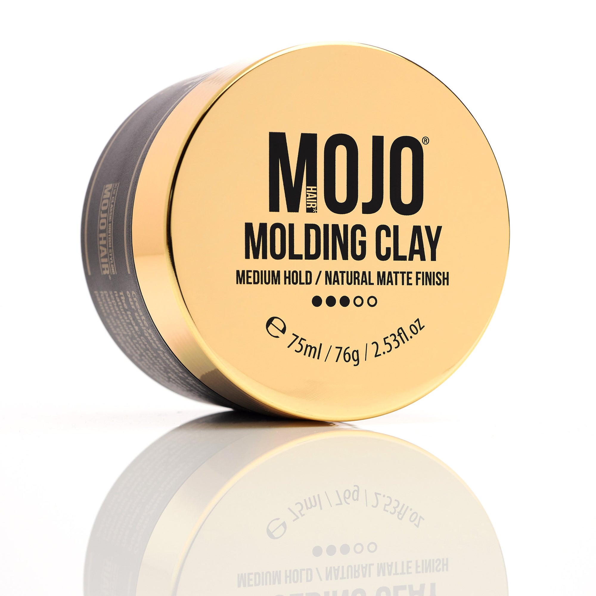 Mojo Hair Molding Clay 75ml Photograph of product featuring gold lid with retro twist designp placed on its' side with full lid facing forward with product description MOJO Hair Logo,Molding Clay Medium Hold/Natural Matte Finish 3/5 dots showing hold factor 75ml/76g/2.53fl.oz with slight drop shadow image of the product on a white background